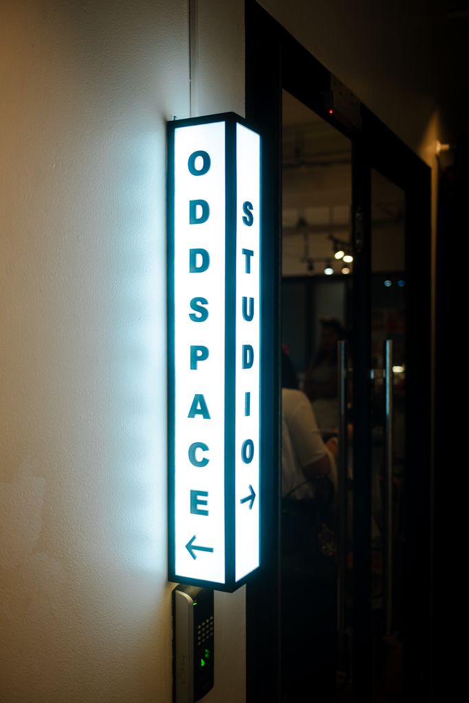 A bright sign for Oddspace Studio highlights the entrance, captured indoors.