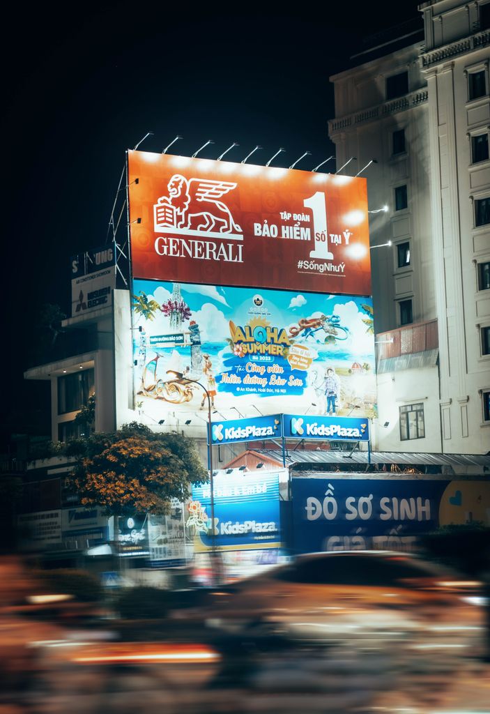 Blurred motion captures a bustling urban street at night with bright billboards.