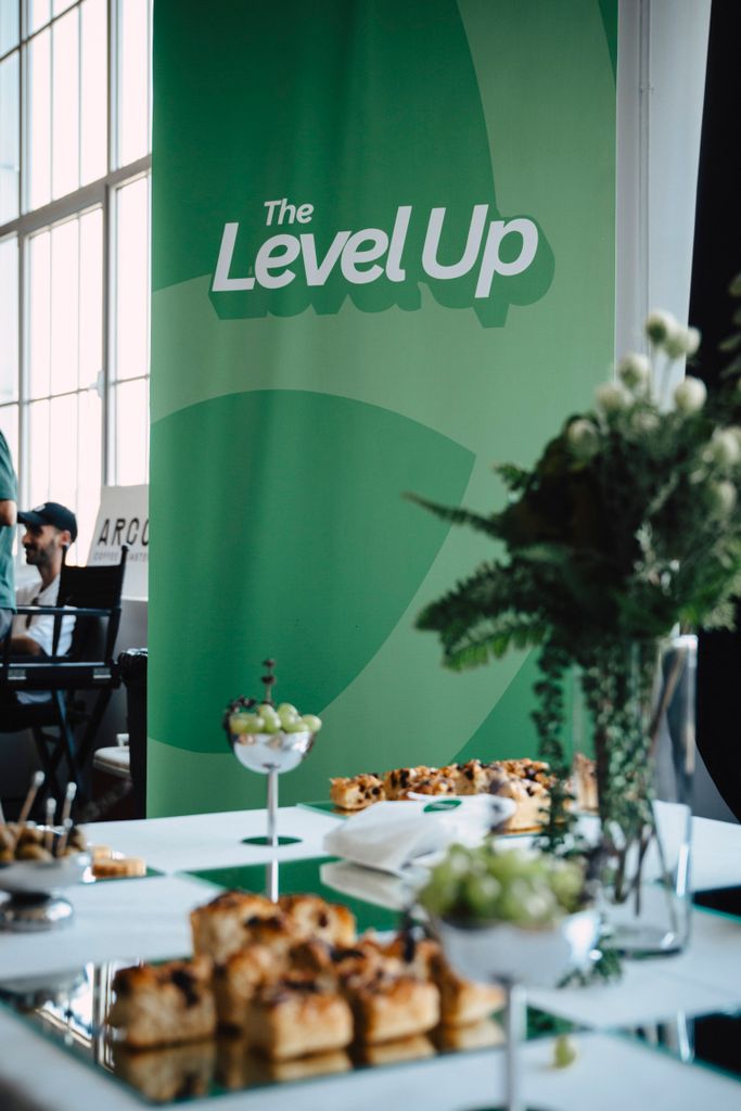 Bright event setup featuring a 'Level Up' banner with snacks and refreshments on a table.