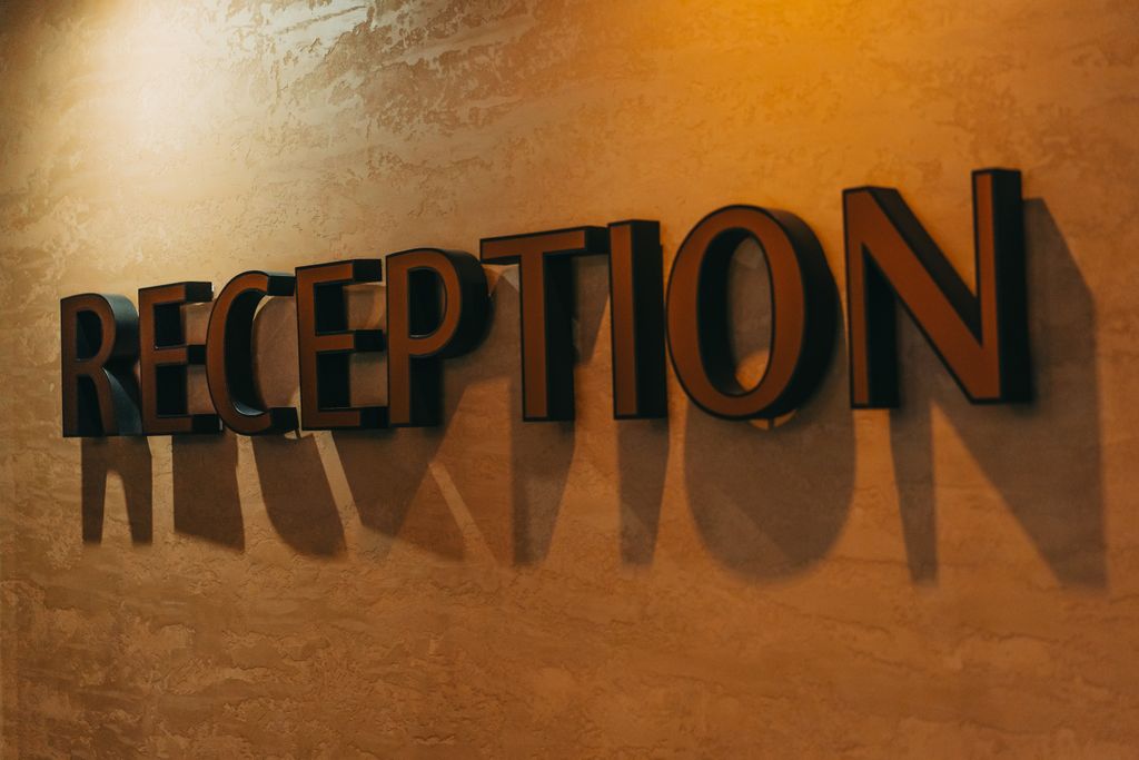 Elegant hotel reception sign casting dramatic shadows on textured wall.