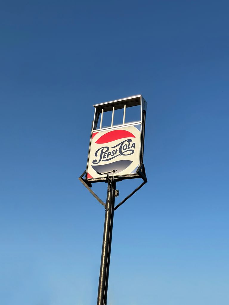 Low angle shot of a Pepsi-Cola sign with a clear blue sky in Sacramento, California.
